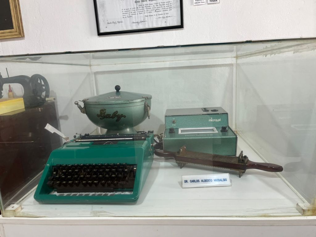 Máquina de escrever verde e objetos antigos em vitrine