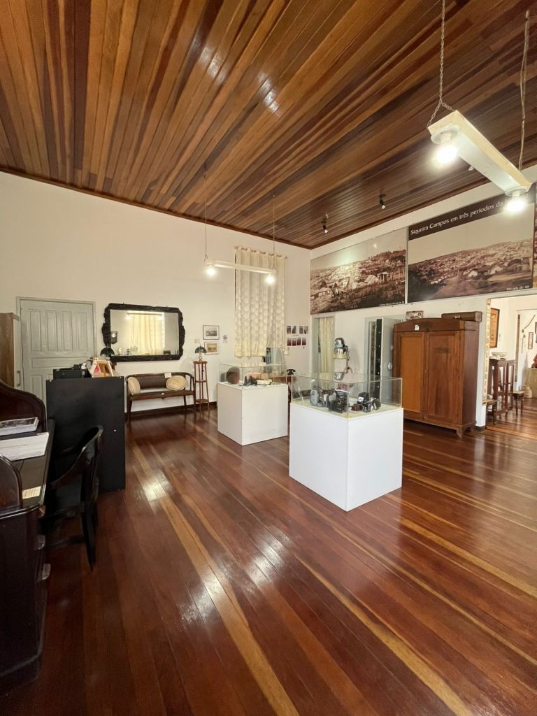 Sala principal do Museu Histórico Municipal com vitrines e assoalho de madeira
