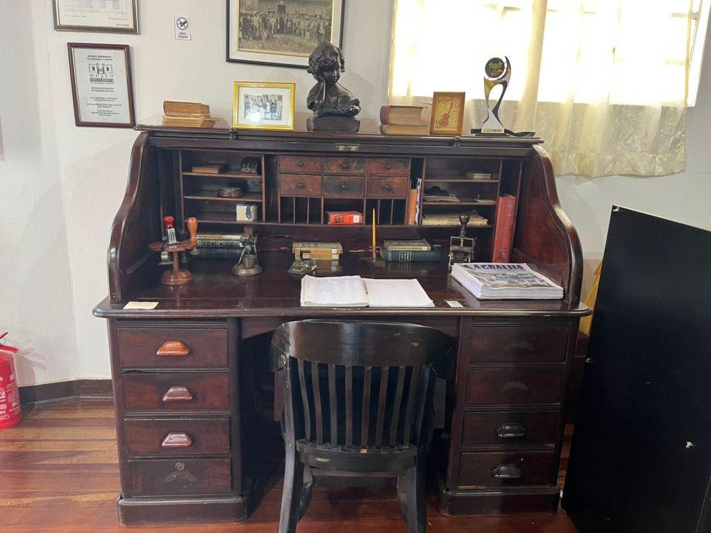 Escrivaninha antiga com livros, documentos e objetos de escritório