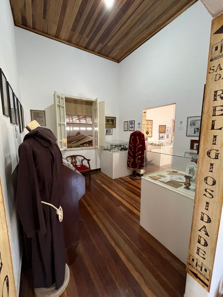 Corredor expositivo com traje religioso e vitrines
